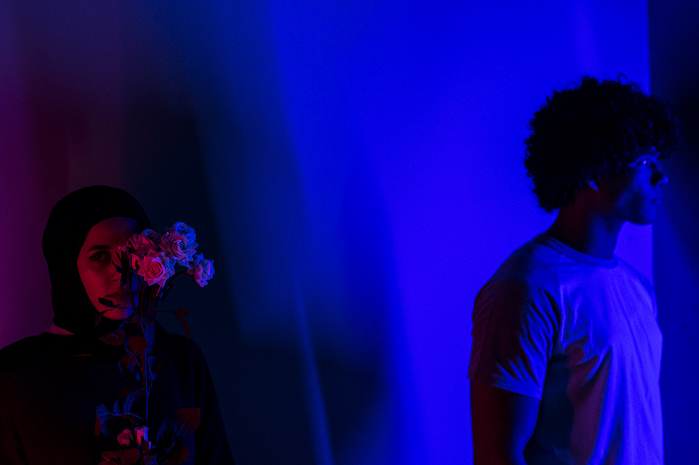 Two figures bathed in blue and magenta
