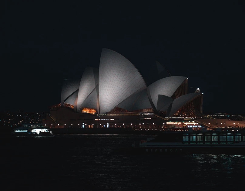 Sydney Opera House lit up at night across the harbour