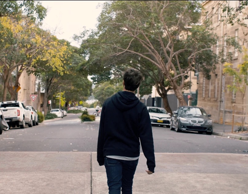 Man walking down a tree-lined suburban street