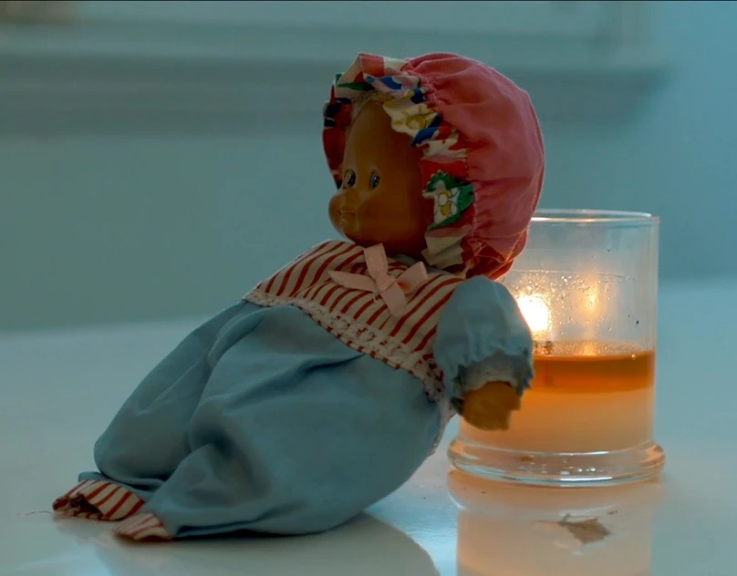 Vintage doll beside a lit candle